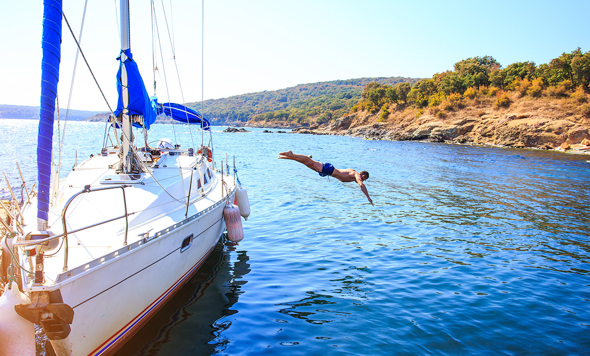 Man diving off of a private yacht, experiencing the best of luxury travel.