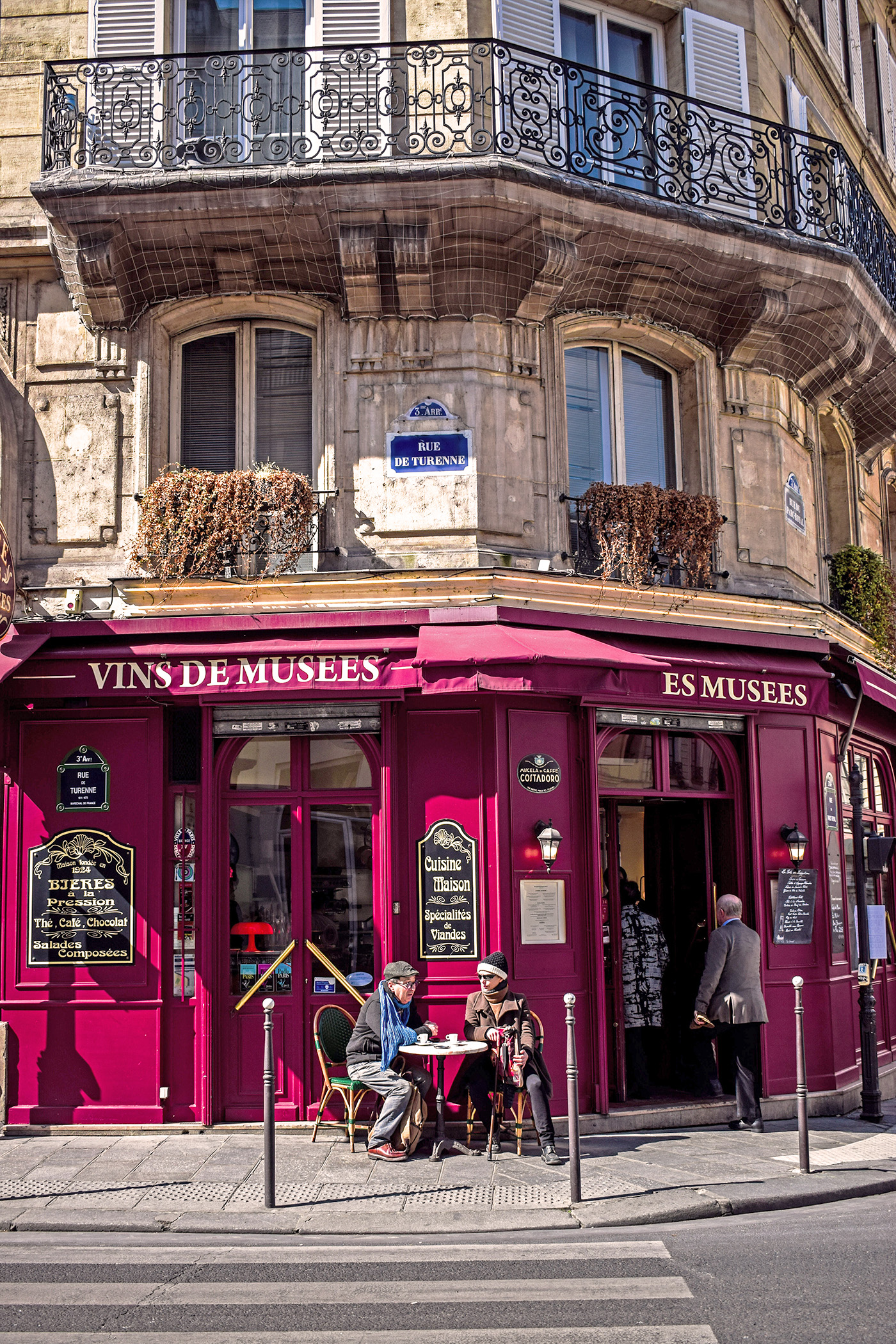 A couple sitting outside a quaint french cafe.