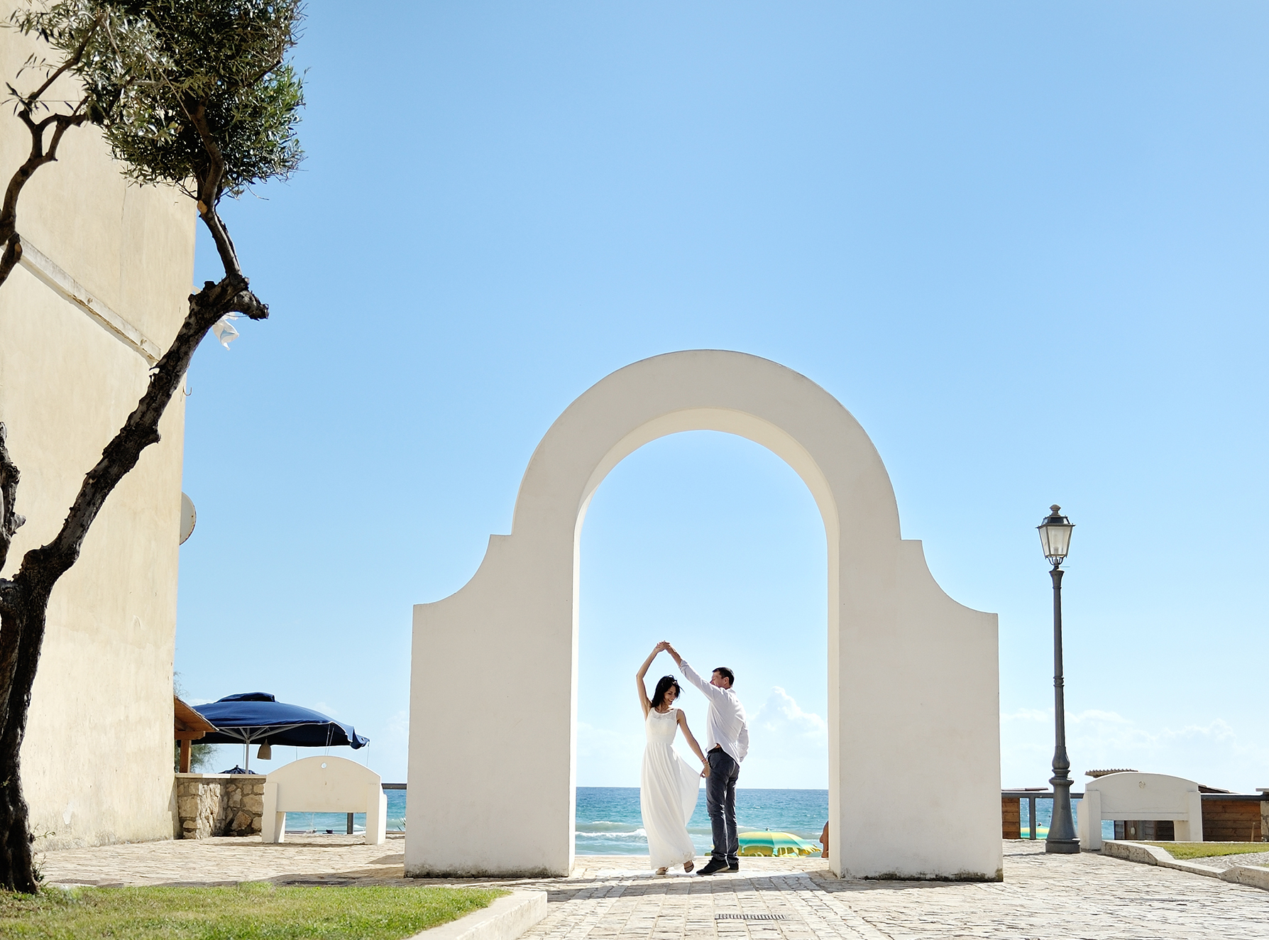 A newly wed couple dancing under a white arch.
